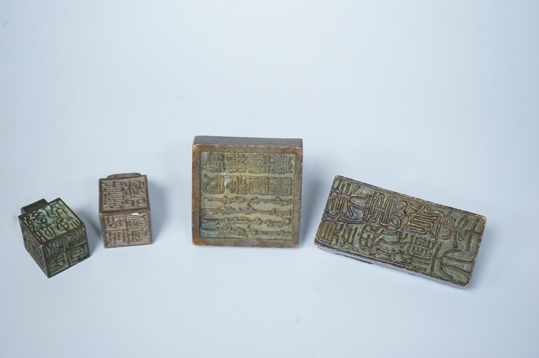 Four Chinese bronze seals, one in the form of two lion dogs, largest 7.5cm wide